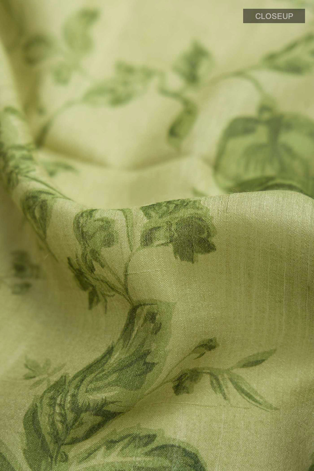 Close up of Green Tussar Silk Saree with Printed design on the body and Zari Border displaying folds