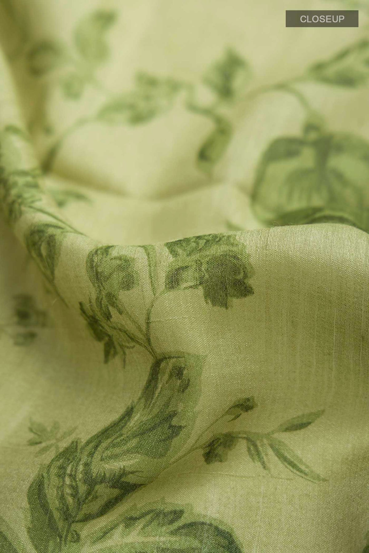 Close up of Green Tussar Silk Saree with Printed design on the body and Zari Border displaying folds