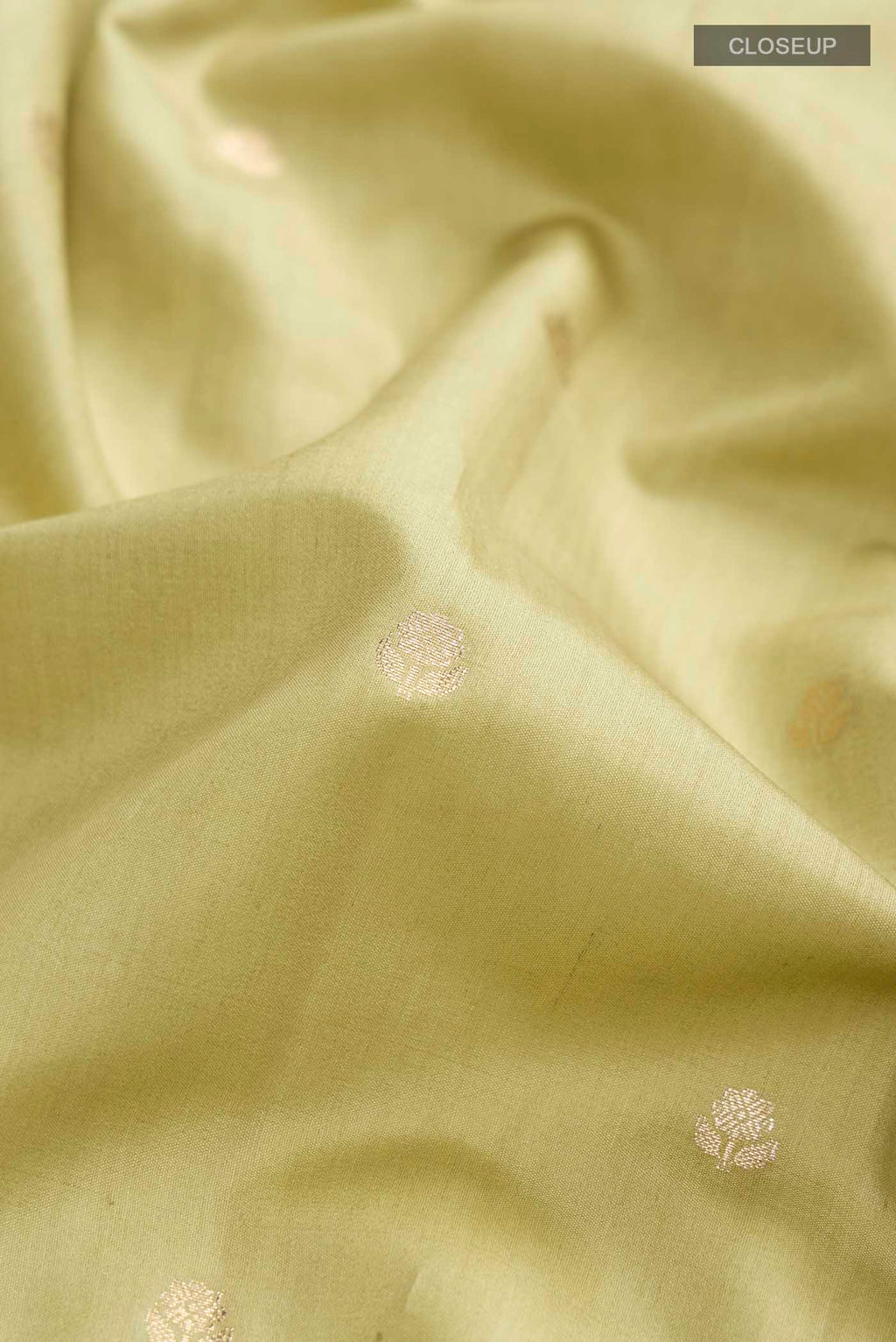 Close up of Green Banarasi Raw Silk Saree with Zari Butta on the body and Zari Border displaying folds