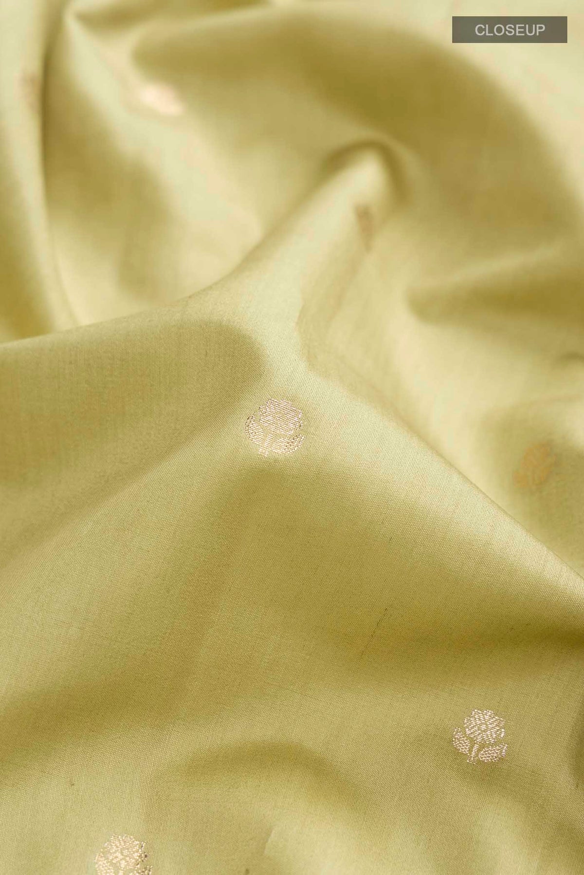 Close up of Green Banarasi Raw Silk Saree with Zari Butta on the body and Zari Border displaying folds