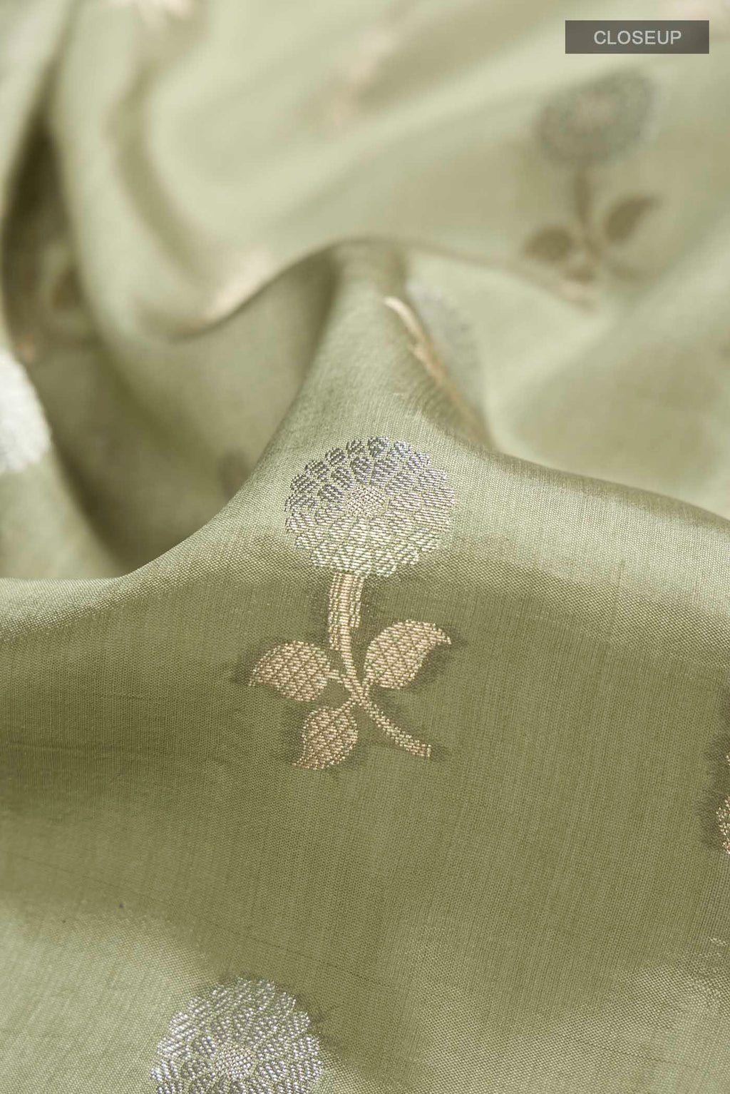 Close up of Green Banarasi Raw Silk Saree with Zari Butta on the body and Zari Border displaying folds