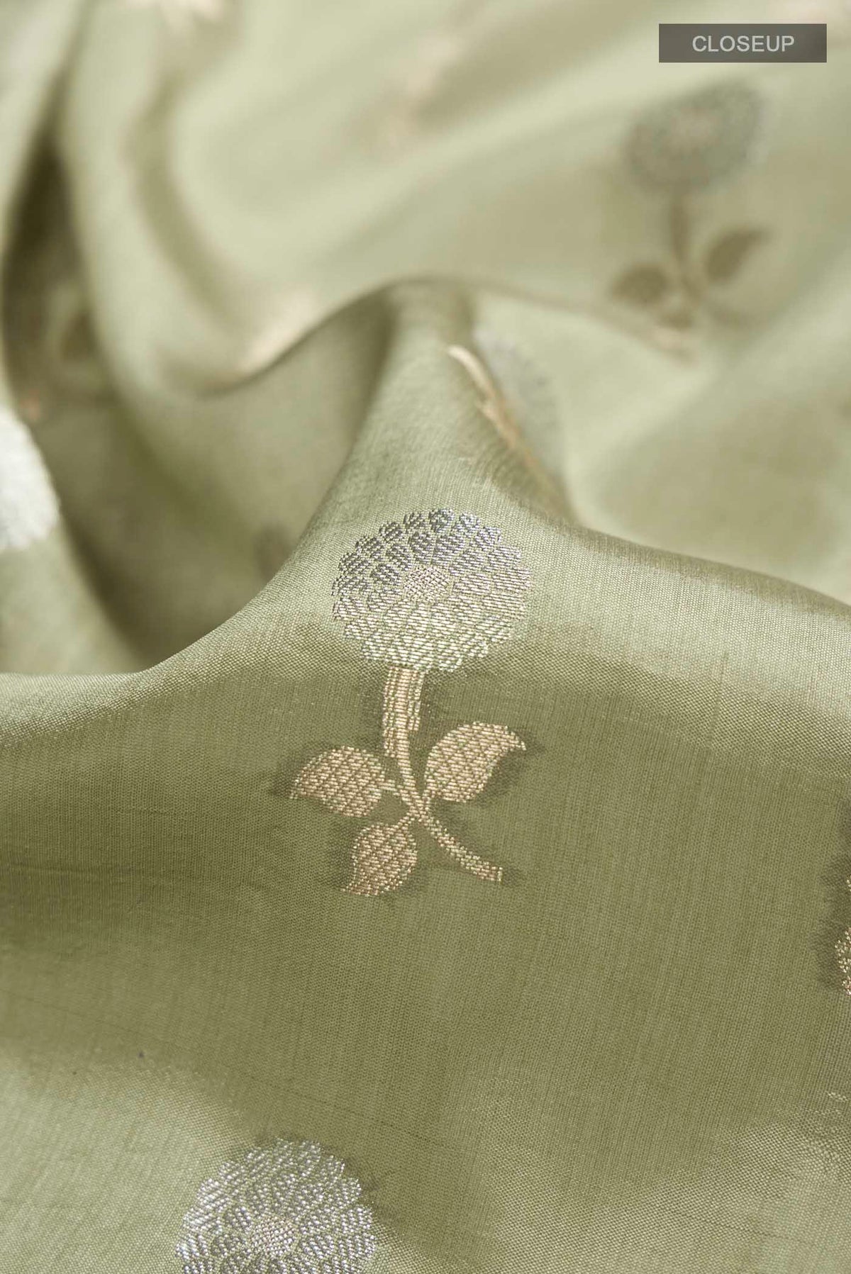 Close up of Green Banarasi Raw Silk Saree with Zari Butta on the body and Zari Border displaying folds
