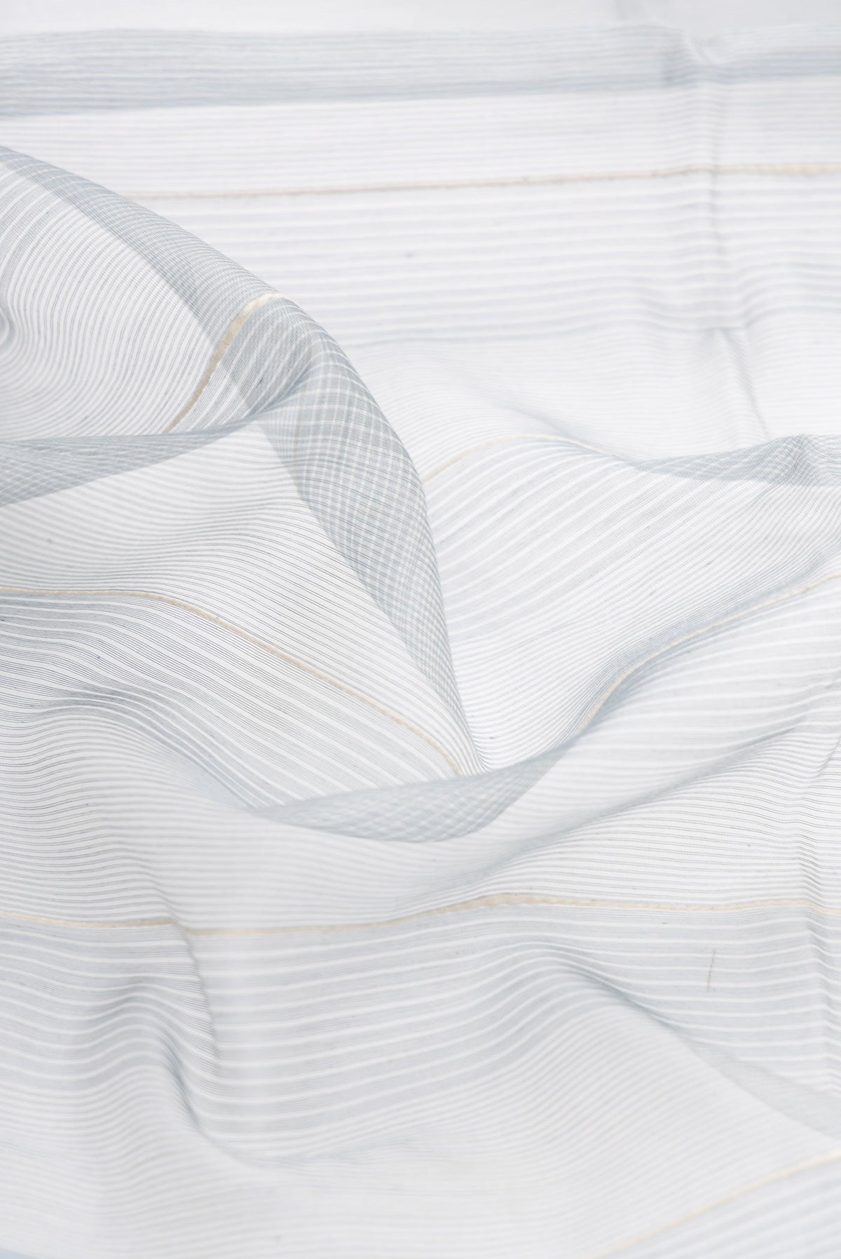 Close up of Grey Dual Tone Silk Cotton Saree with Stripes on the body and Zari Border displaying folds