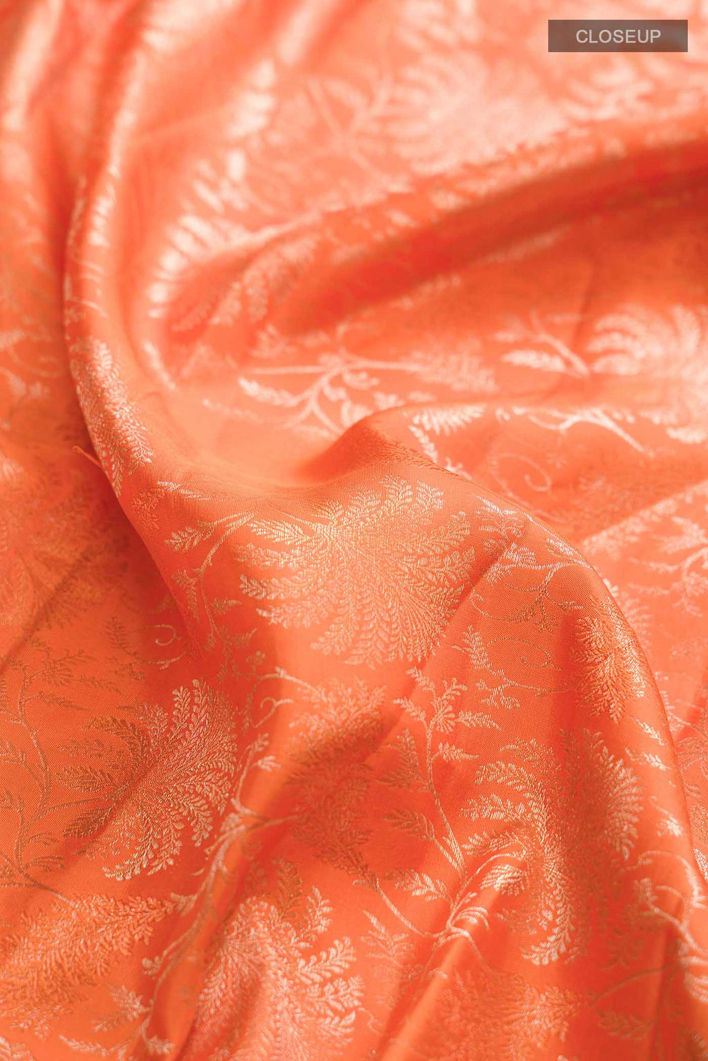 Close up of Orange Kanchipuram Silk Saree with Zari Brocade on the body and Zari Border displaying folds