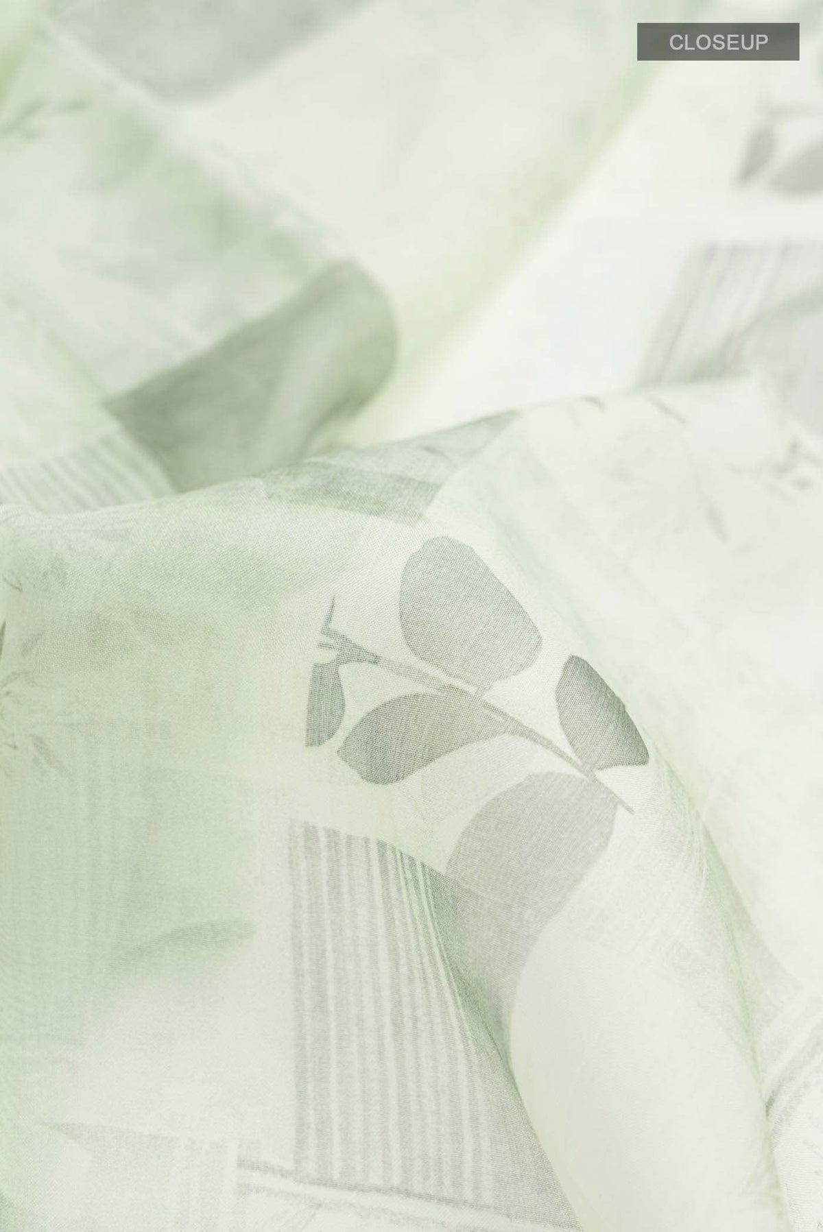 Close up of Green Organza Silk Saree with Printed design on the body and Plain Border displaying folds