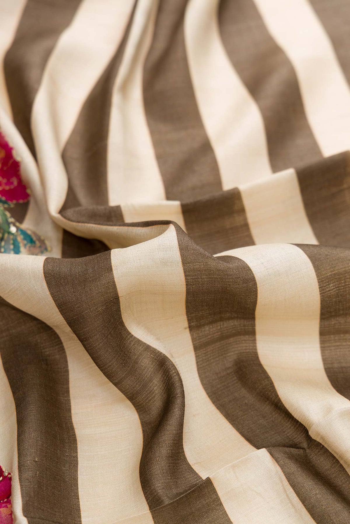 Close up of Dark Beige and Sandal Color Tussar Silk Saree with Printed design on the body and Fancy Border displaying folds