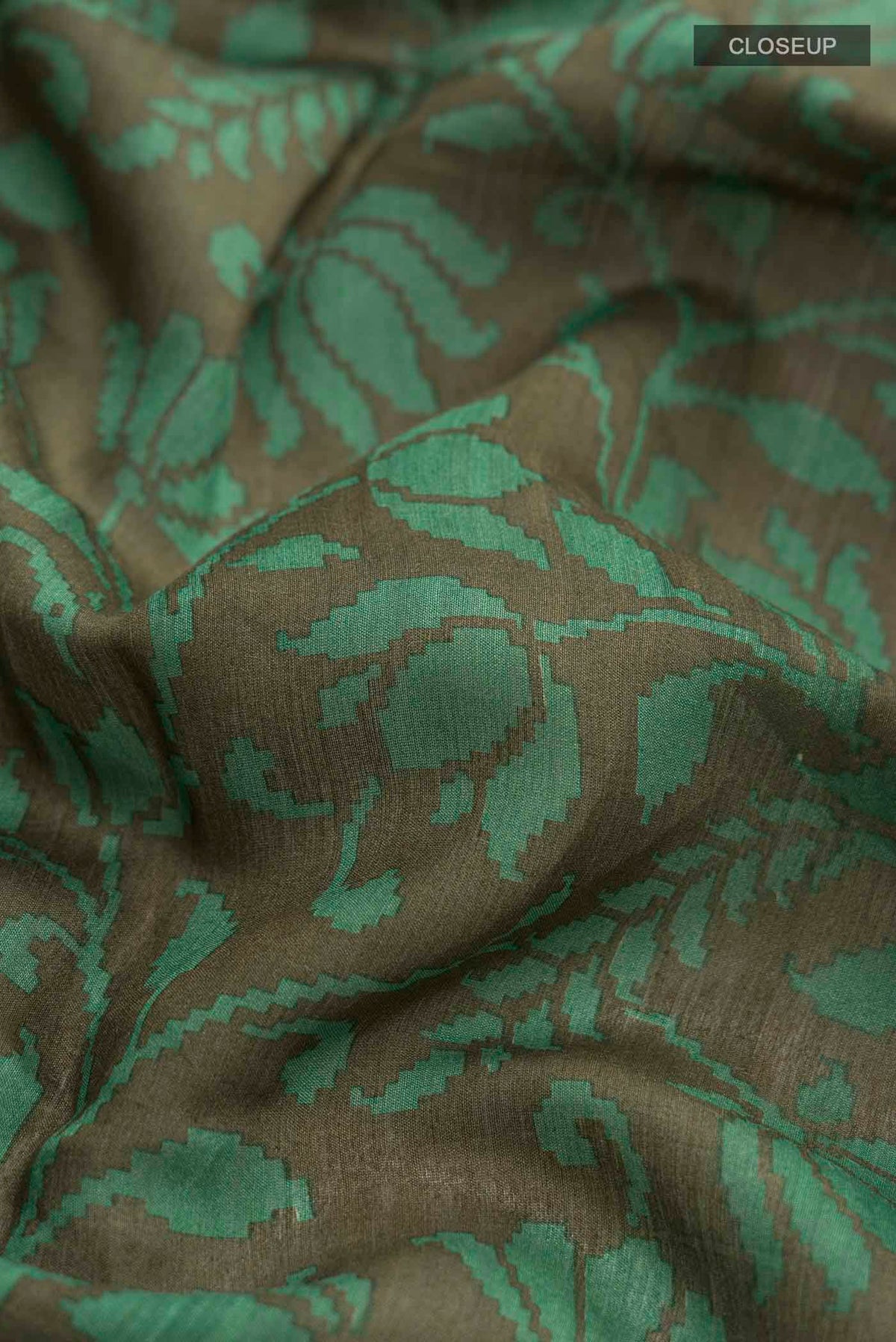 Close up of Green Tussar Silk Saree with Printed design on the body and Zari Border displaying folds