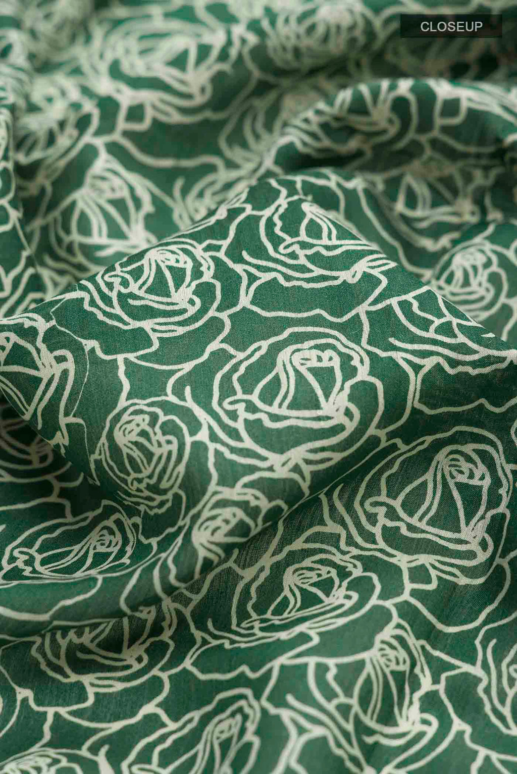 Close up of Green Tussar Silk Saree with Printed design on the body and Zari Border displaying folds