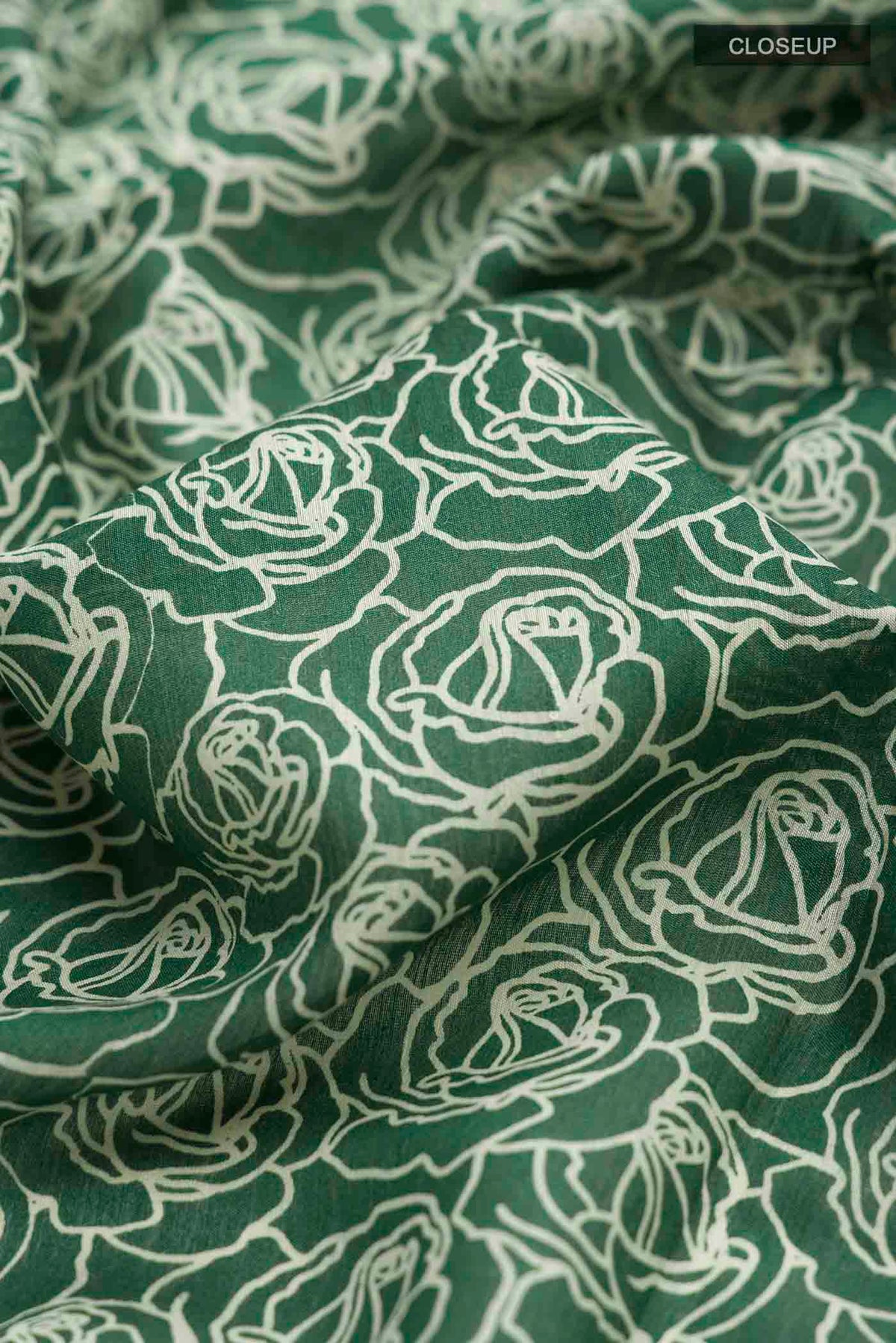 Close up of Green Tussar Silk Saree with Printed design on the body and Zari Border displaying folds