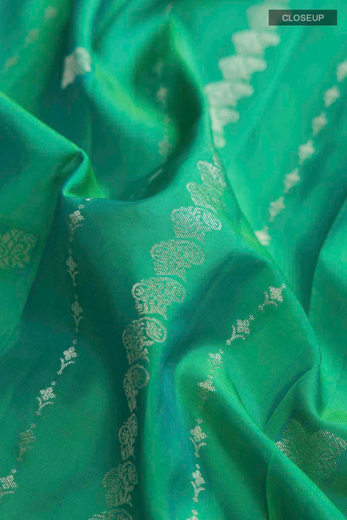 Close up of Green Kanchipuram Silk Saree with Zari Butta on the body and Zari Border displaying folds