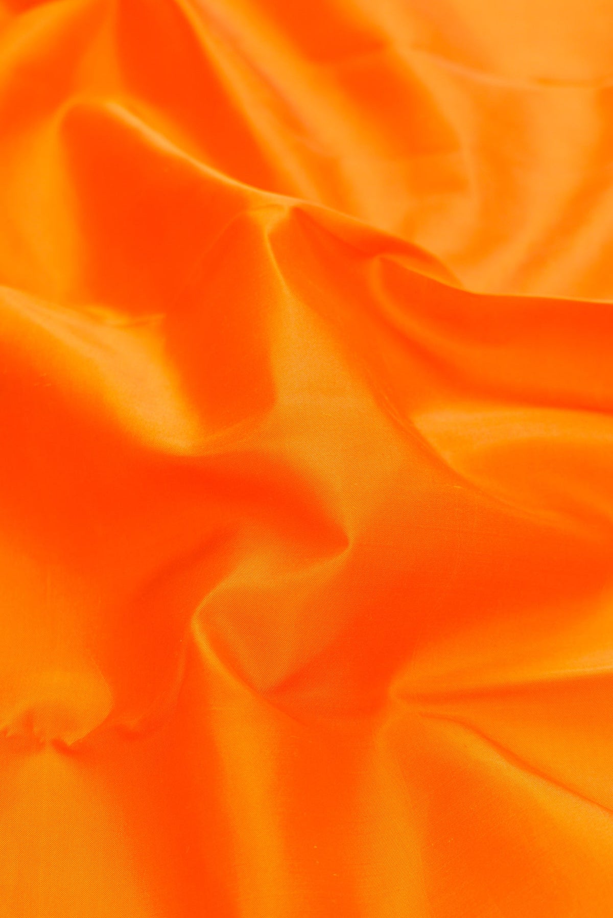 Close up of Orange Dual Tone Kanchipuram Silk Saree with Plain Body and Ganga Jamuna Border.  displaying folds