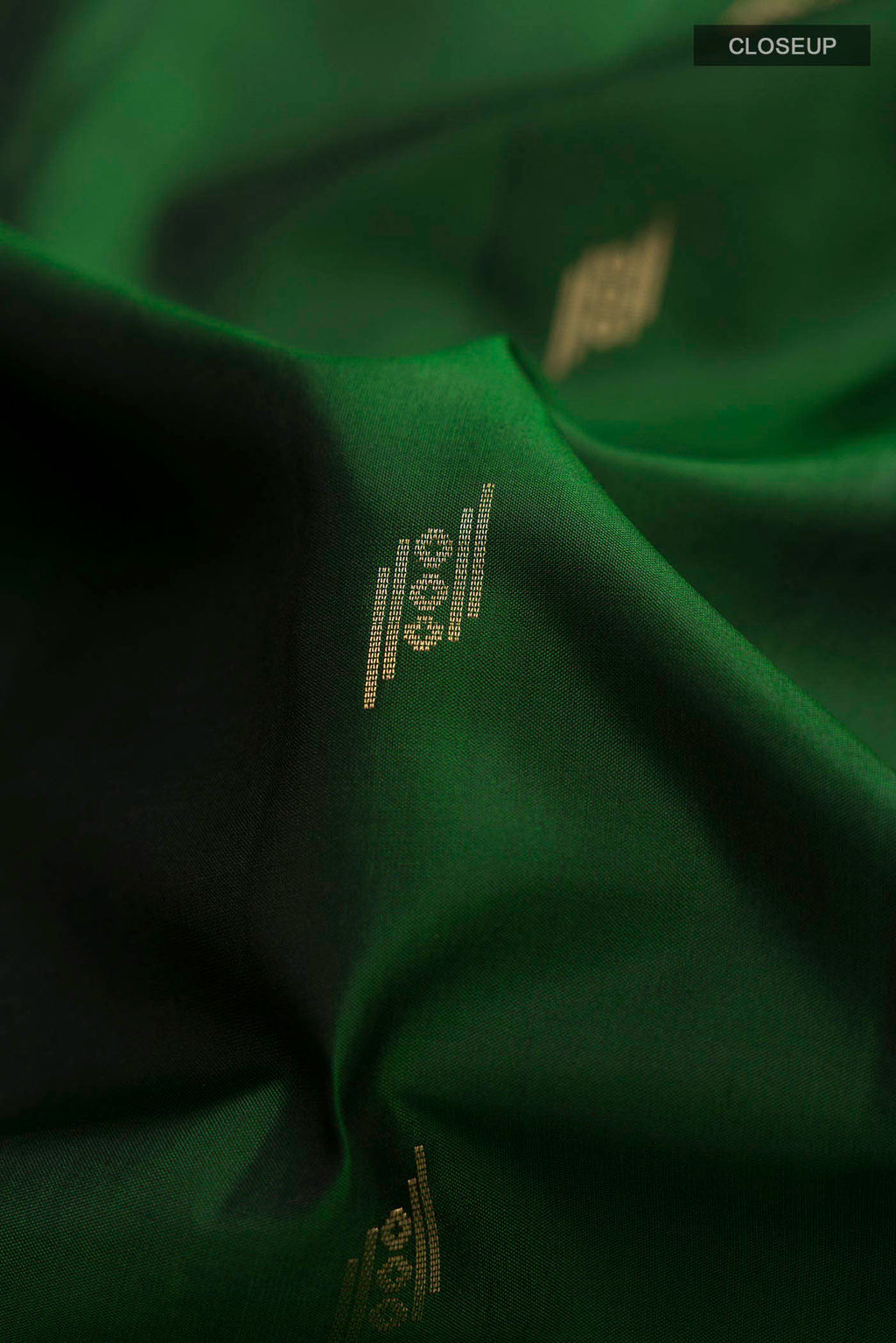 Close up of Green Soft Silk Saree with Zari Butta on the body and Zari Border displaying folds