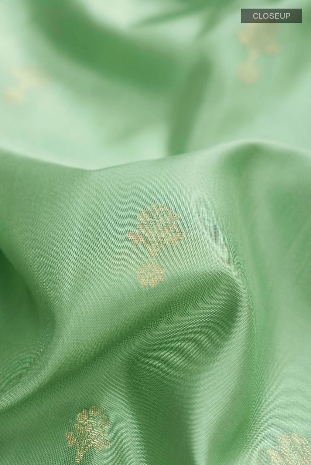 Close up of Green Soft Silk Saree with Zari Butta on the body and Zari Border displaying folds