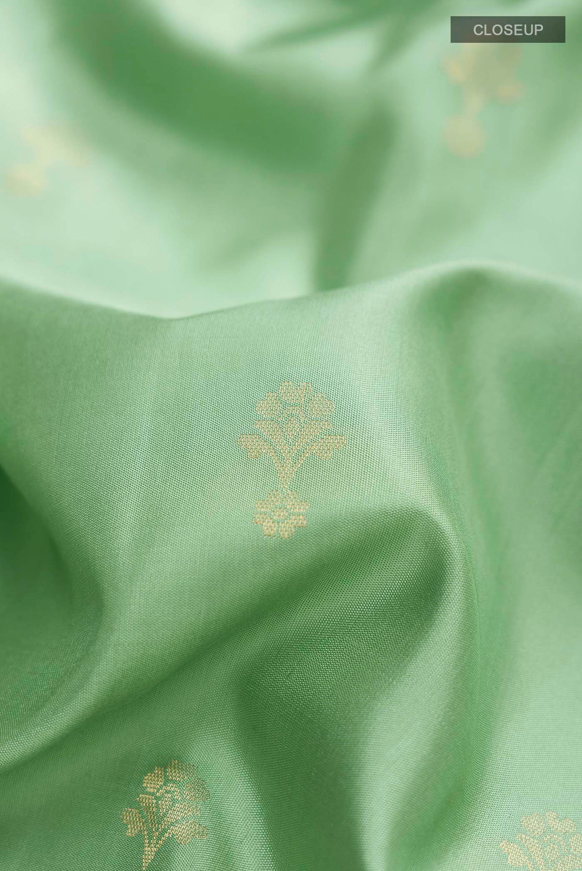 Close up of Green Soft Silk Saree with Zari Butta on the body and Zari Border displaying folds