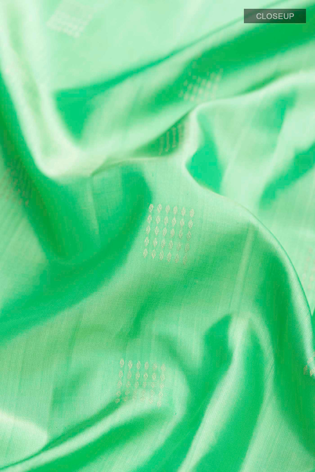 Close up of Green Soft Silk Saree with Zari Butta on the body and Zari Border displaying folds