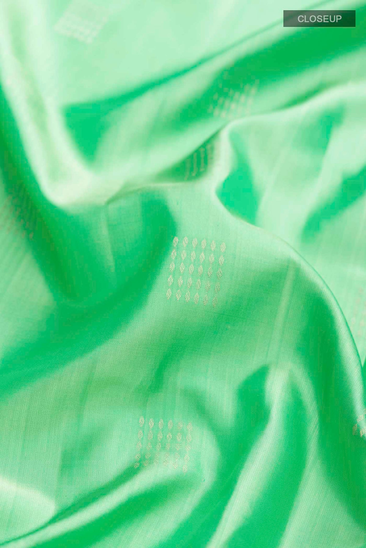 Close up of Green Soft Silk Saree with Zari Butta on the body and Zari Border displaying folds
