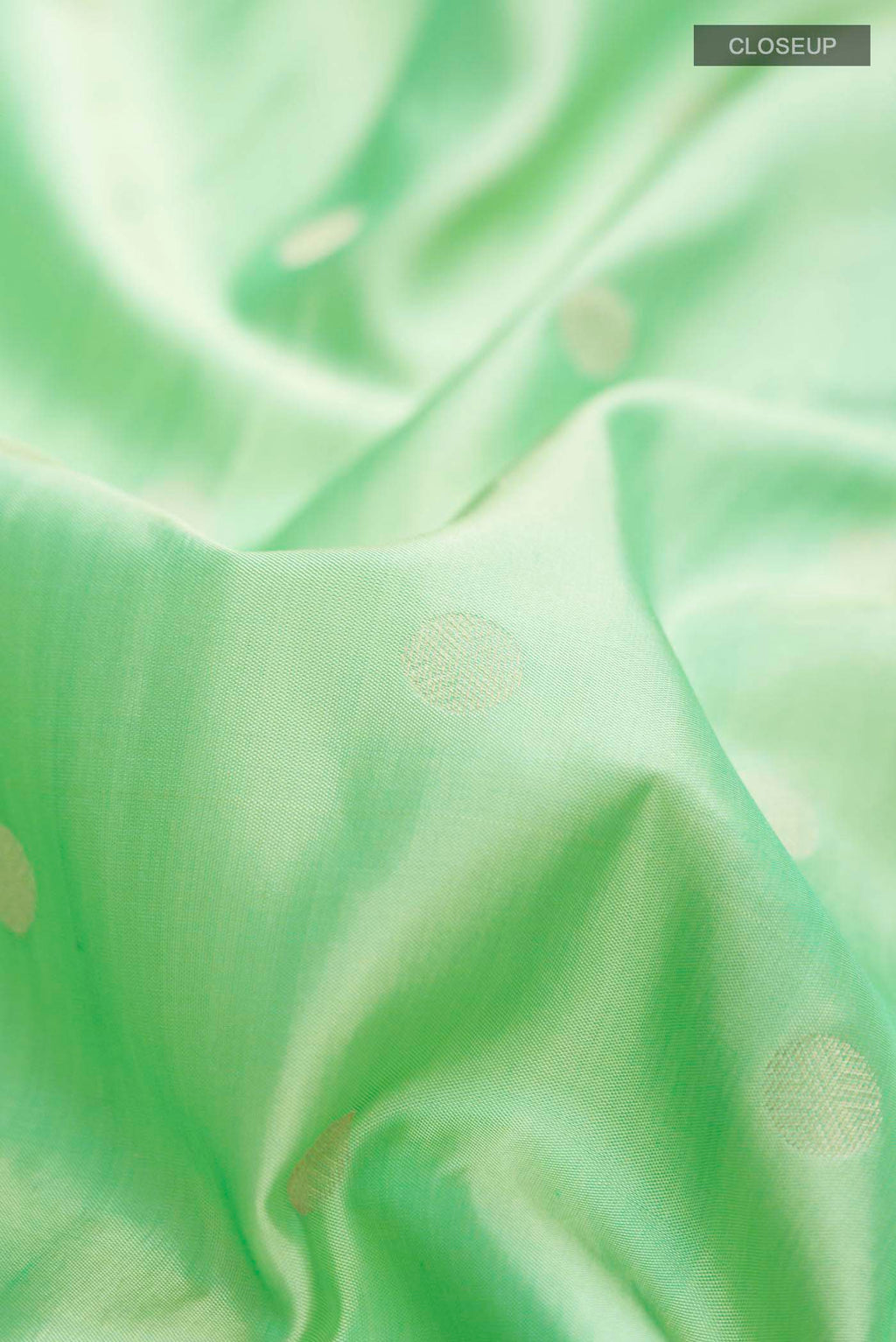 Close up of Green Soft Silk Saree with Zari Butta on the body and Zari Border displaying folds