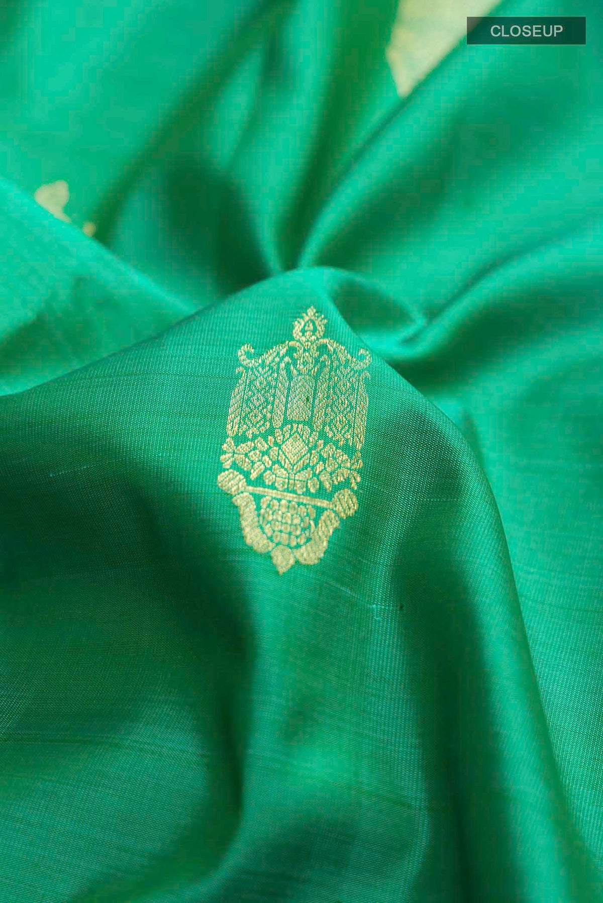 Close up of Green Kanchipuram Silk Saree with Zari Butta on the body and Zari Border displaying folds