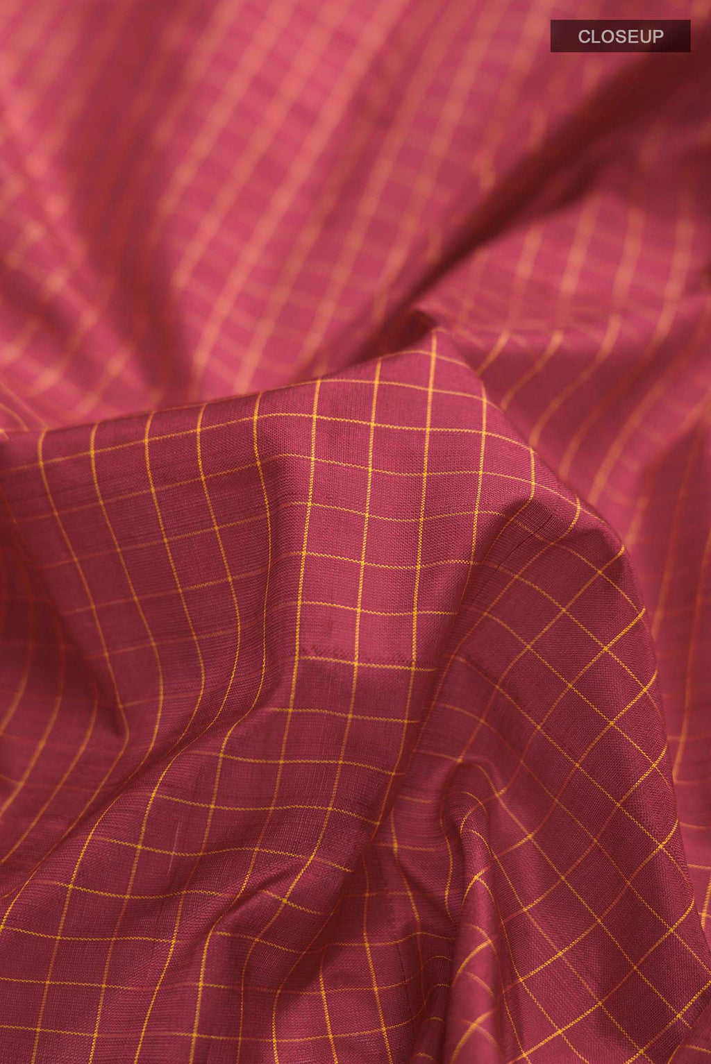 Close up of Maroon Kanchipuram Silk Saree with Checked design on the body and Zari Border displaying folds