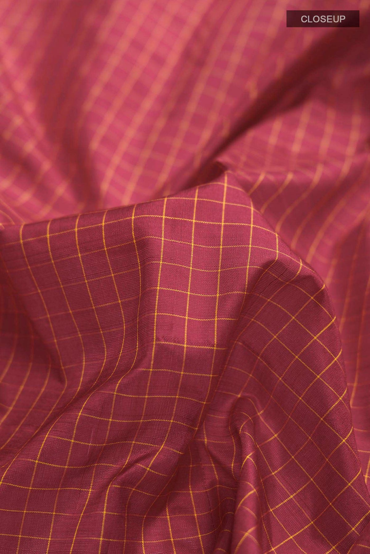 Close up of Maroon Kanchipuram Silk Saree with Checked design on the body and Zari Border displaying folds