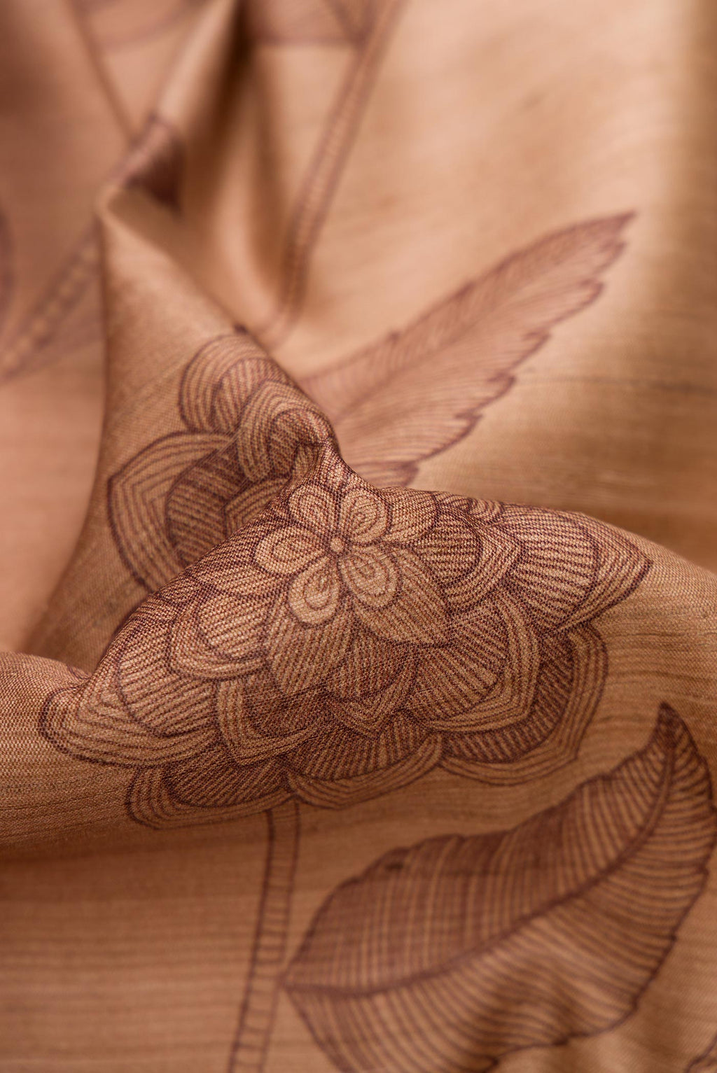 Close up of Brown Dual Tone Tussar Silk Saree with Printed design on the body and Embroidery Border.  displaying folds