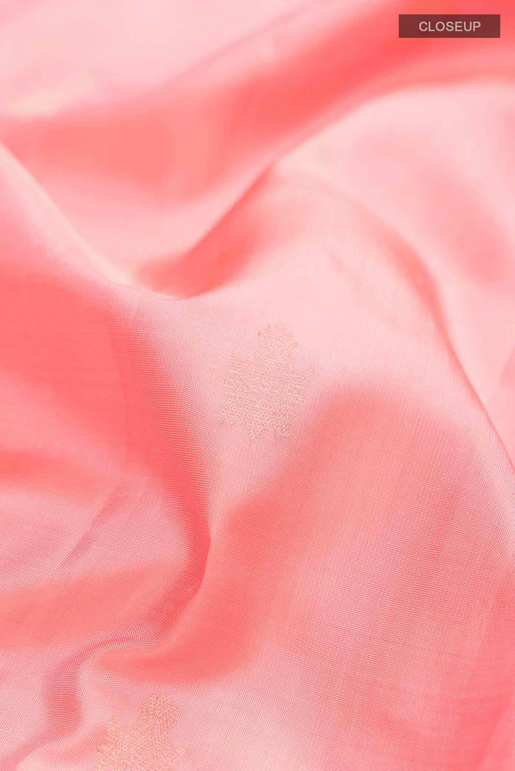 Close up of Coral Soft Silk Saree with Zari Butta on the body and Zari Border displaying folds