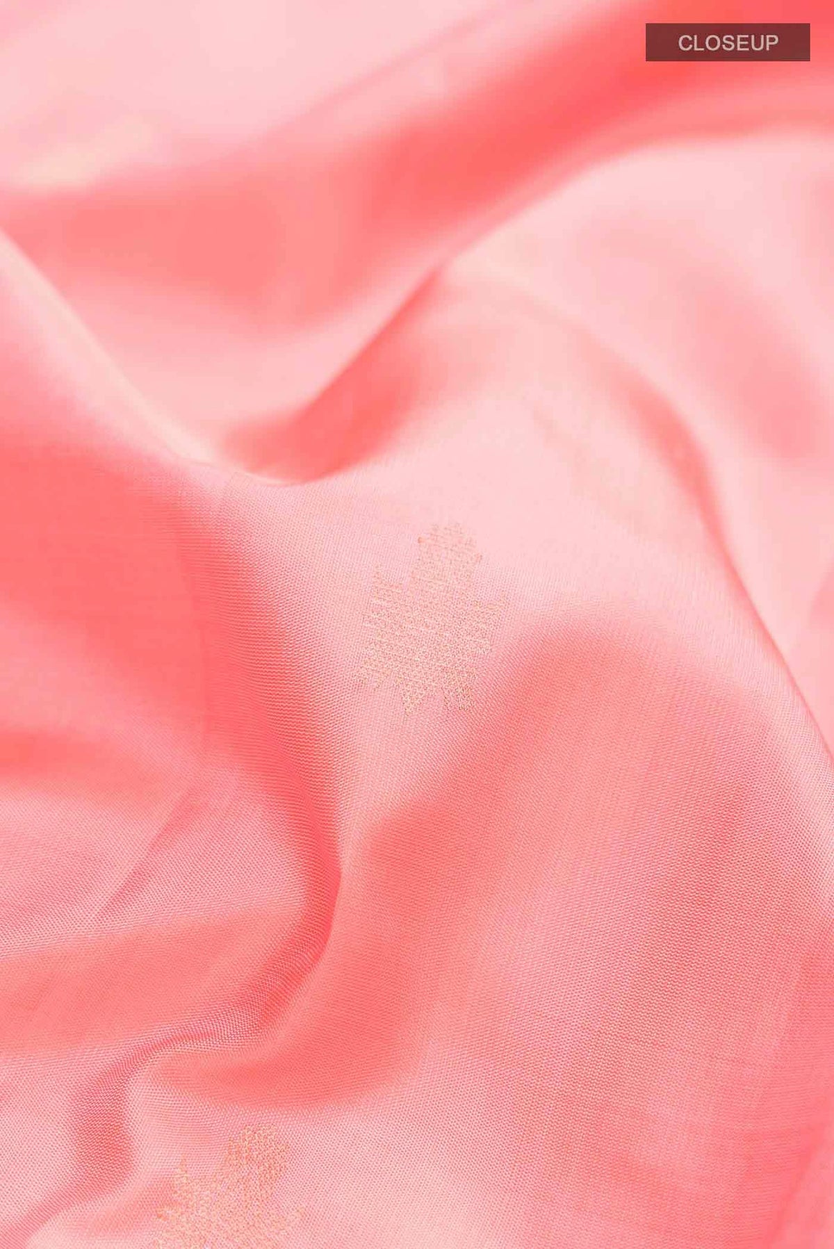 Close up of Coral Soft Silk Saree with Zari Butta on the body and Zari Border displaying folds