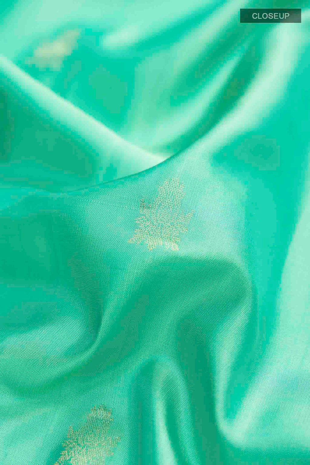 Close up of Green Soft Silk Saree with Zari Butta on the body and Zari Border displaying folds