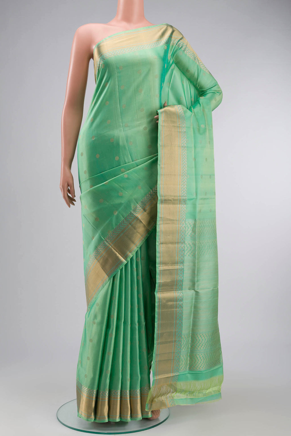 Green Soft Silk Saree with Zari Butta on the body and Zari Border displayed on a mannequin