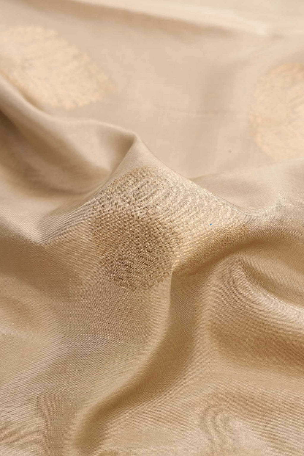 Close up of Beige Dual Tone Soft Silk Saree with Zari Butta on the body and Zari Border displaying folds