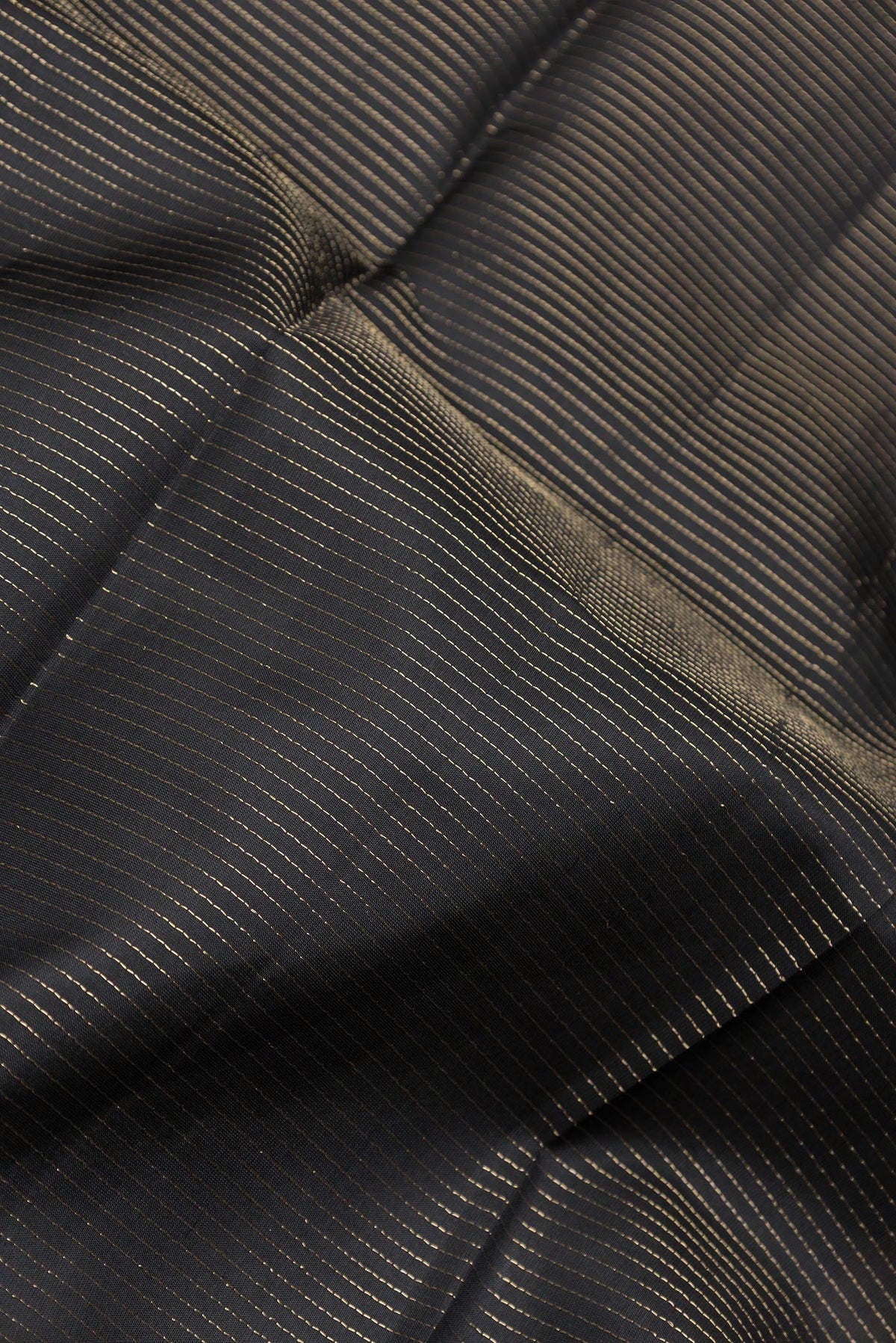 Close up of Black Dual Tone Kanchipuram Silk Saree with Stripes on the body and Zari Border.  displaying folds