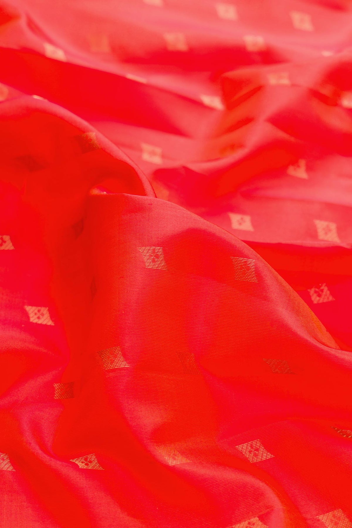 Close up of Orange Dual Tone Kanchipuram Silk Saree with Zari Butta on the body and Zari Border displaying folds