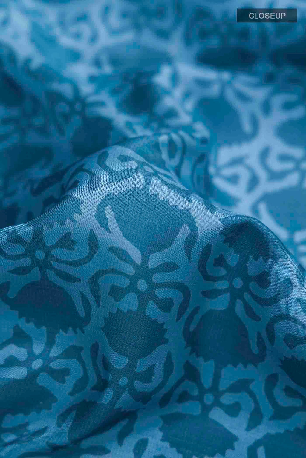 Close up of Blue Printed Silk Saree with Printed design on the body and Plain Border displaying folds
