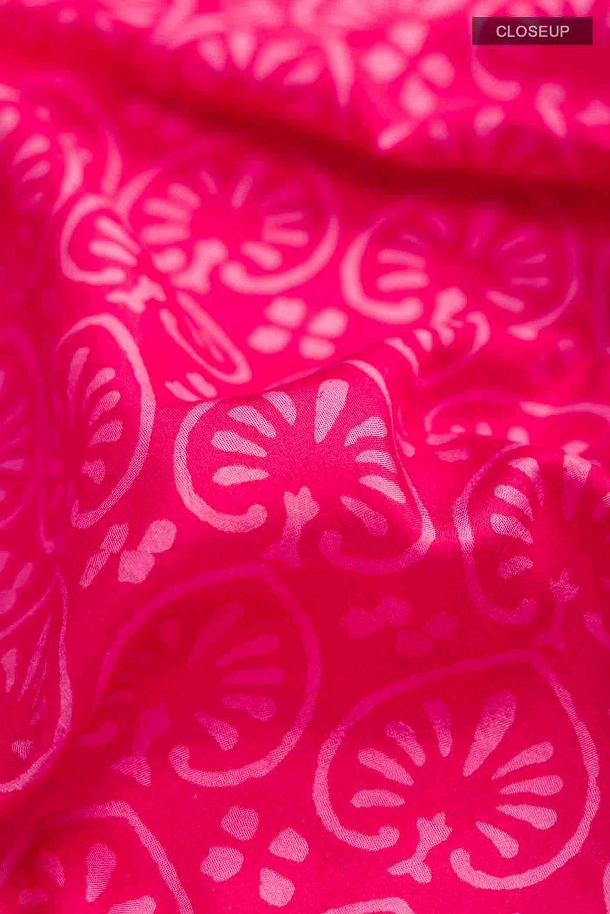 Close up of Pink Printed Silk Saree with Printed design on the body and Zari Border displaying folds