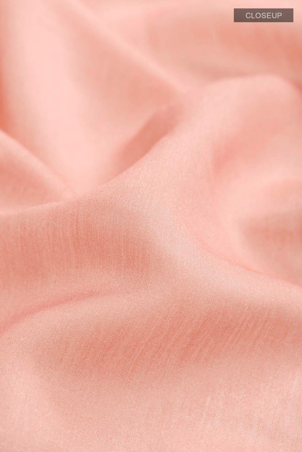 Close up of Peach Tussar Silk Saree with Embroidery on the body and Zari And Thread Border displaying folds