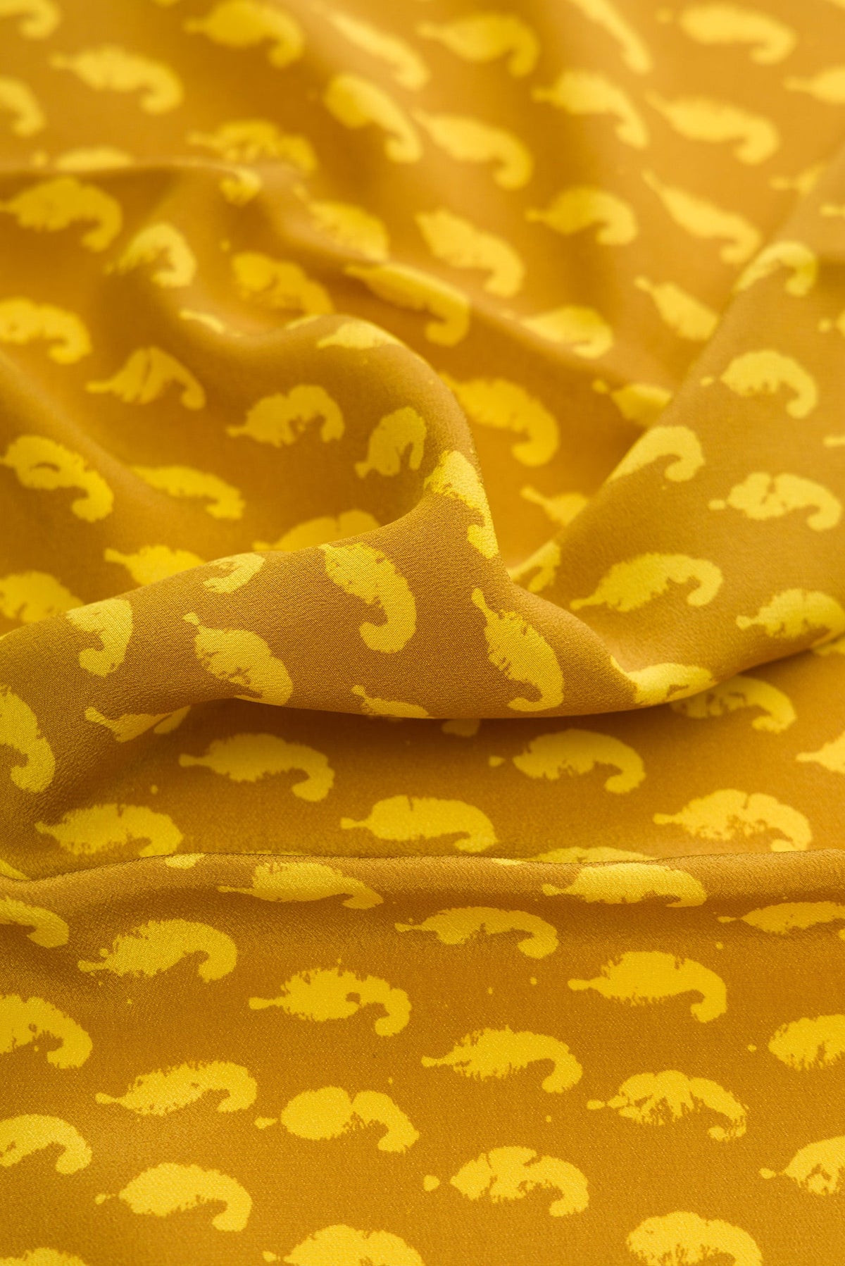 Close up of Mustard Dual Tone Mysore Crepe Saree with Printed design on the body and Printed Border.  displaying folds