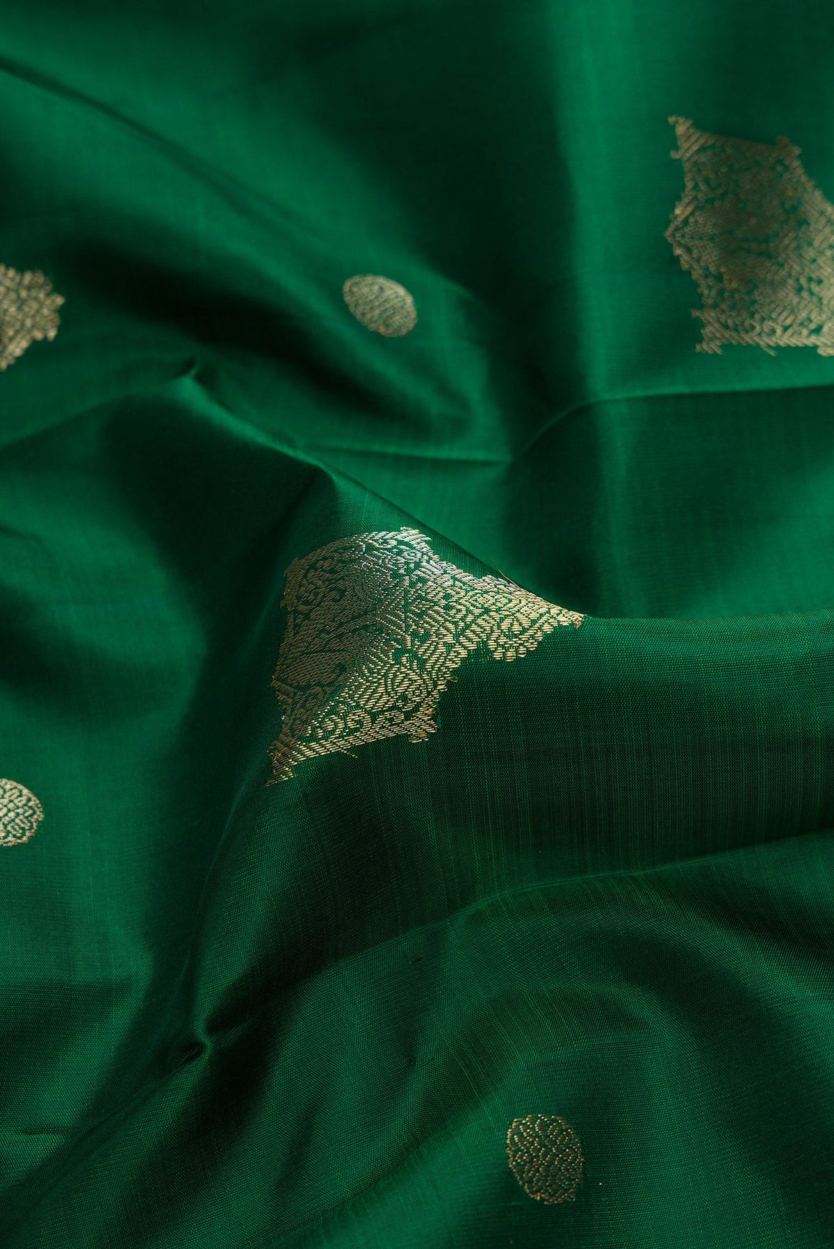 Close up of Green Dual Tone Kanjivaram Silk Saree with Zari Butta on the body and Zari Border.  displaying folds