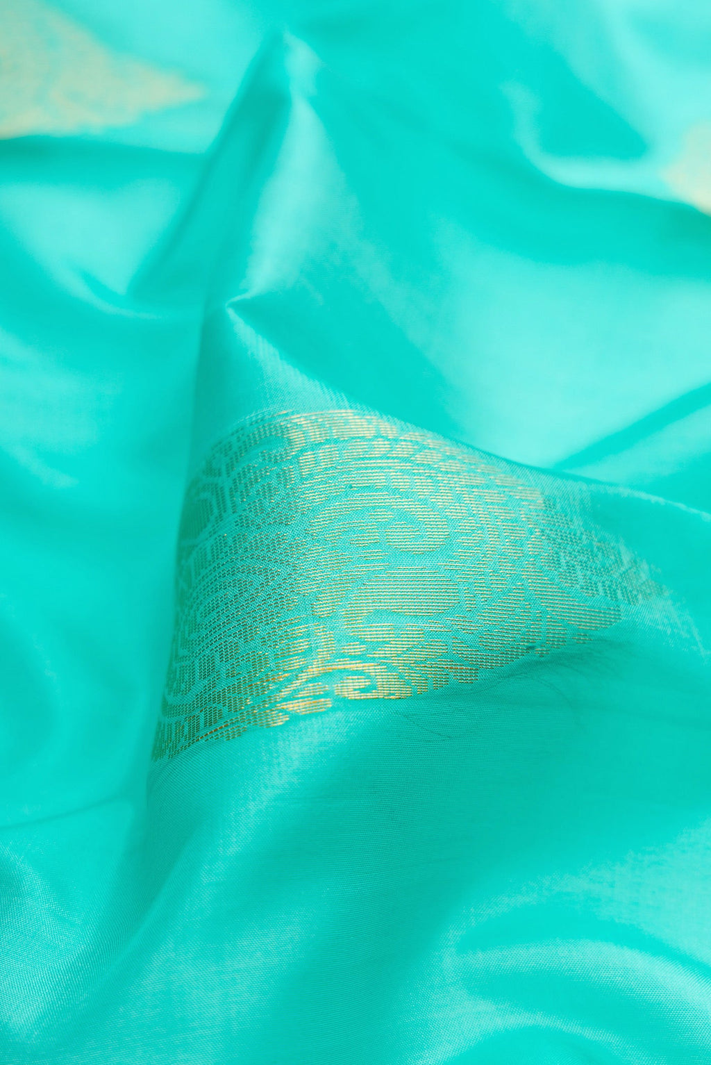 Close up of Sky Blue Soft Silk Saree with Zari Butta on the body and Zari Border.  displaying folds