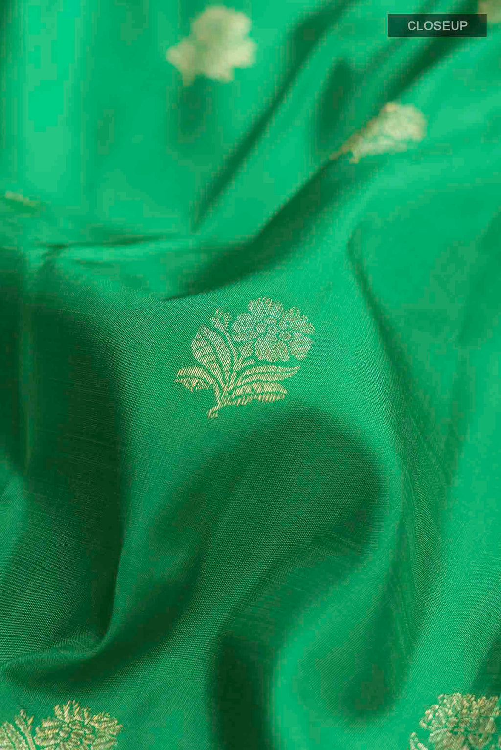 Close up of Green Kanchipuram Silk Saree with Zari Butta on the body and Zari Border displaying folds