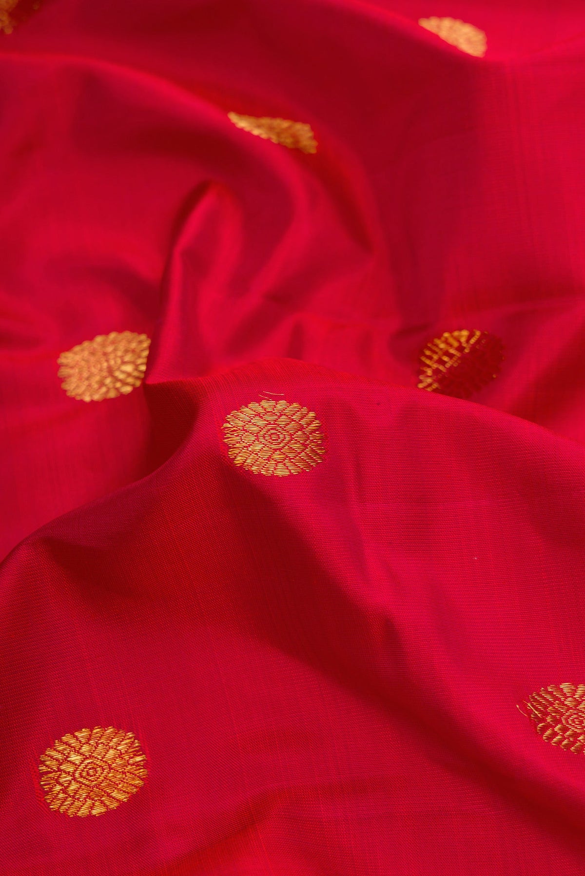 Close up of Red Dual Tone Kanchipuram Silk Saree with Zari Butta on the body and Zari Border.  displaying folds