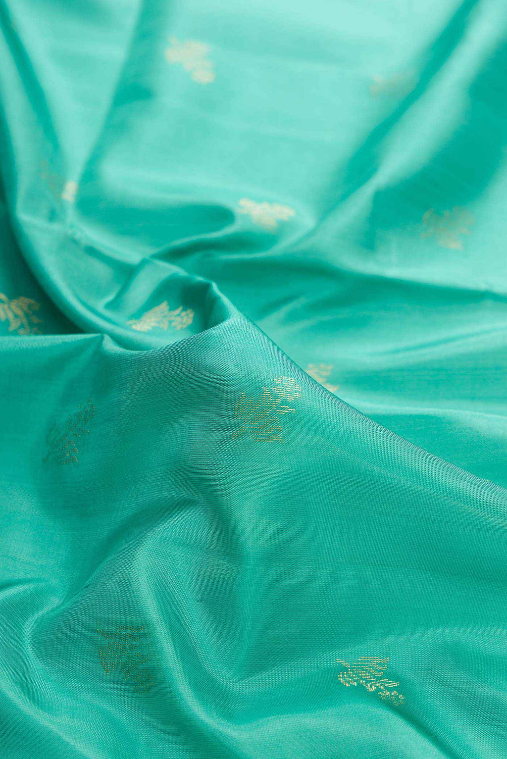 Close up of Green Dual Tone Soft Silk Saree with Zari Butta on the body and Zari Border displaying folds