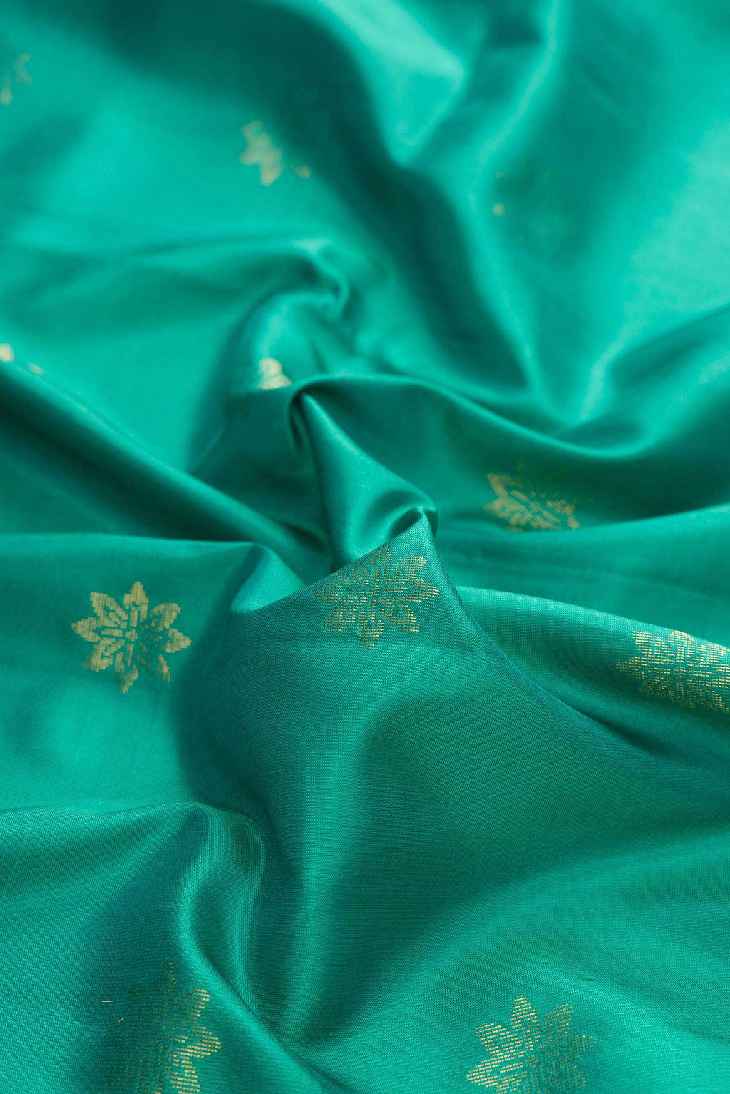 Close up of Green Dual Tone Soft Silk Saree with Zari Butta on the body and Zari Border displaying folds