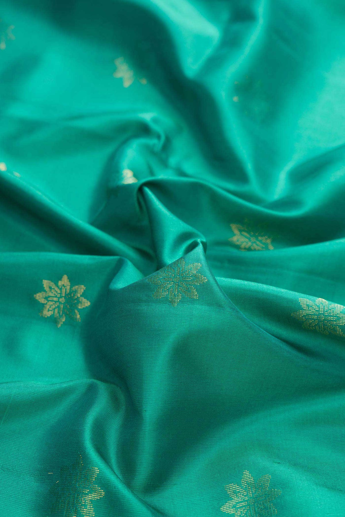 Close up of Green Dual Tone Soft Silk Saree with Zari Butta on the body and Zari Border displaying folds