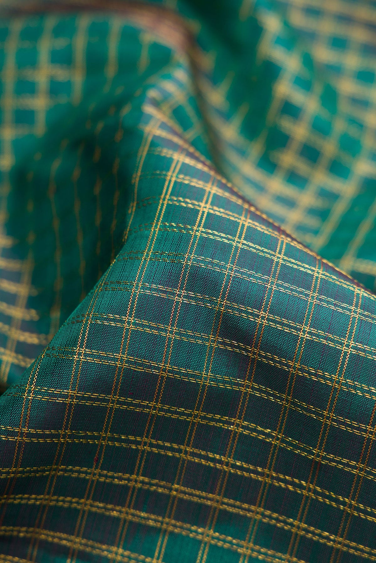 Close up of Green Dual Tone Kanjivaram Silk Saree with Checked design on the body and Zari Border.  displaying folds