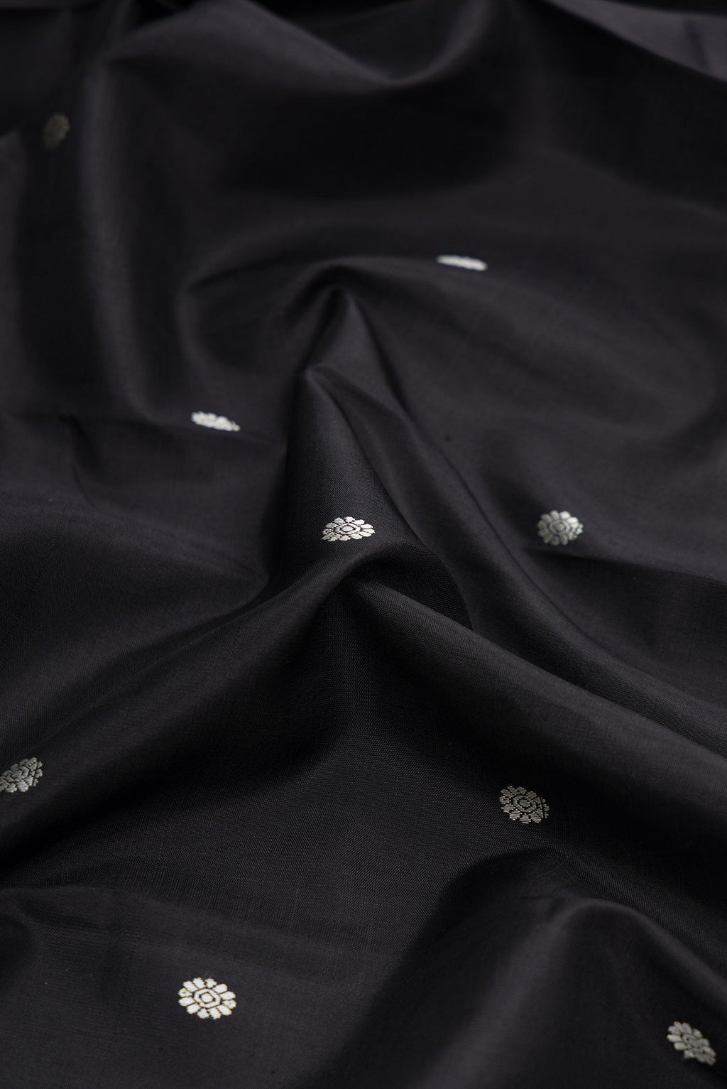 Close up of Black Dual Tone Kanchipuram Silk Saree with Thread Butta on the body and Zari Border displaying folds