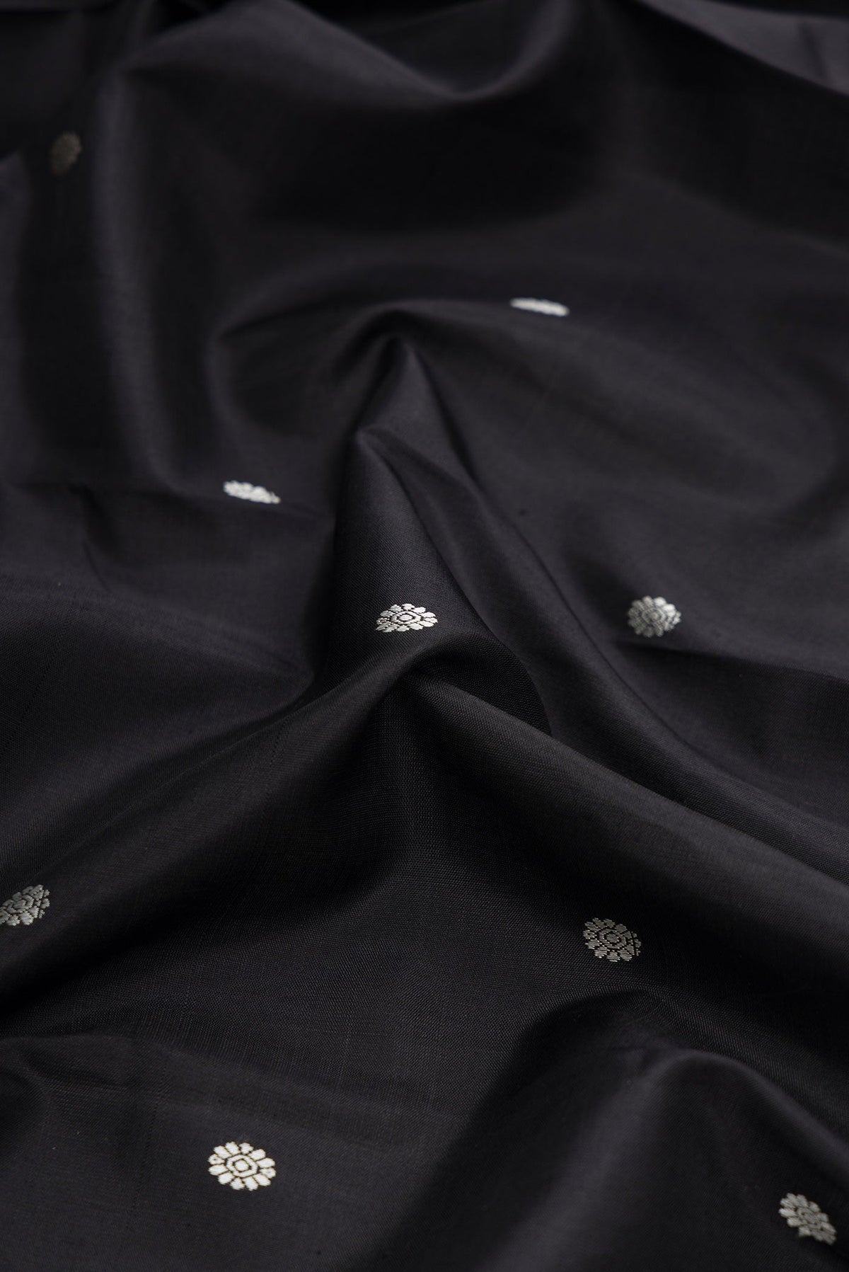 Close up of Black Dual Tone Kanchipuram Silk Saree with Thread Butta on the body and Zari Border displaying folds
