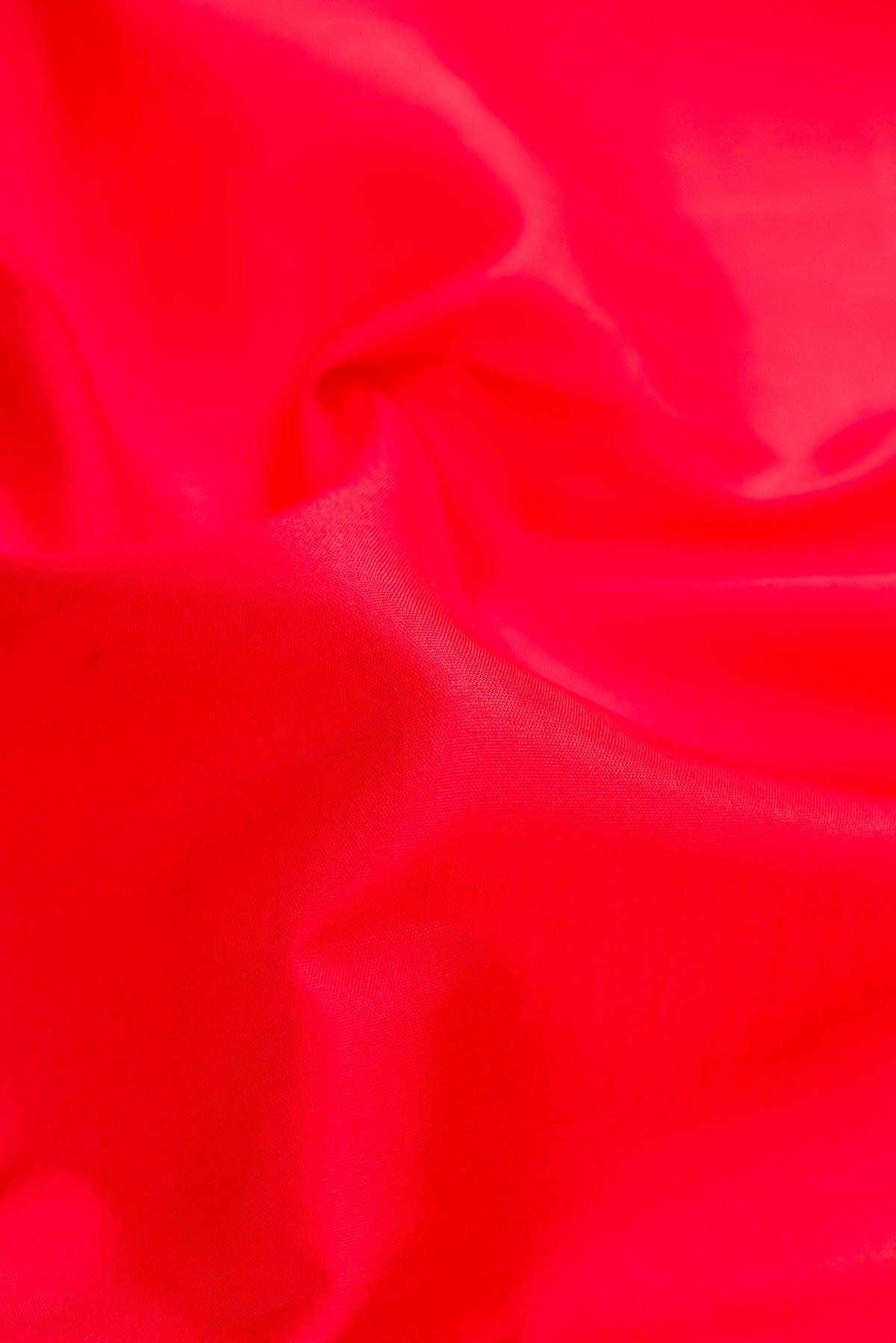 Close up of Red Dual Tone Kanjivaram Silk Saree with Plain Body and Zari Border.  displaying folds
