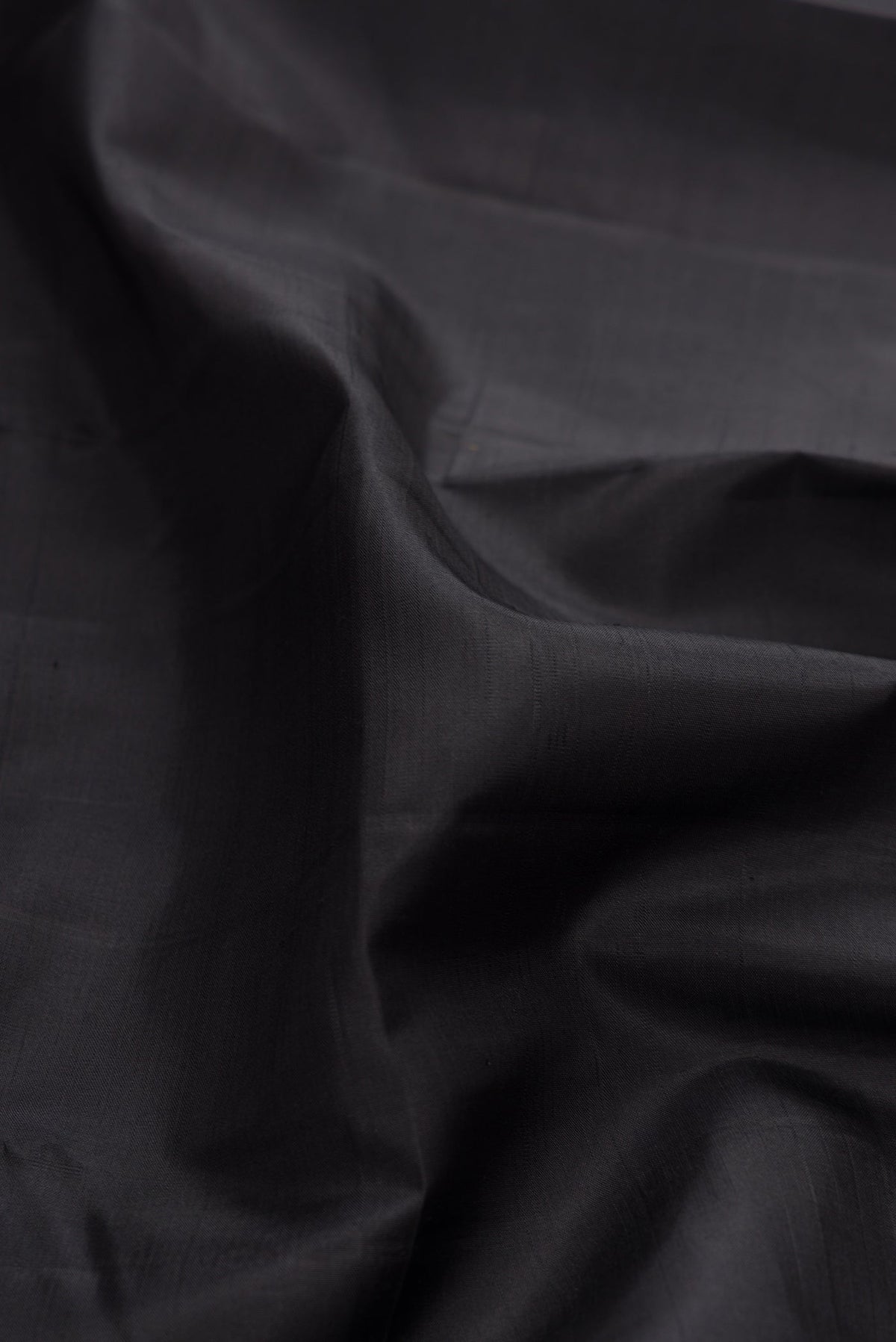 Close up of Pure Silk Pure Zari Black Dual Tone Kanchipuram Saree with Plain Body and Checks Border.  displaying folds