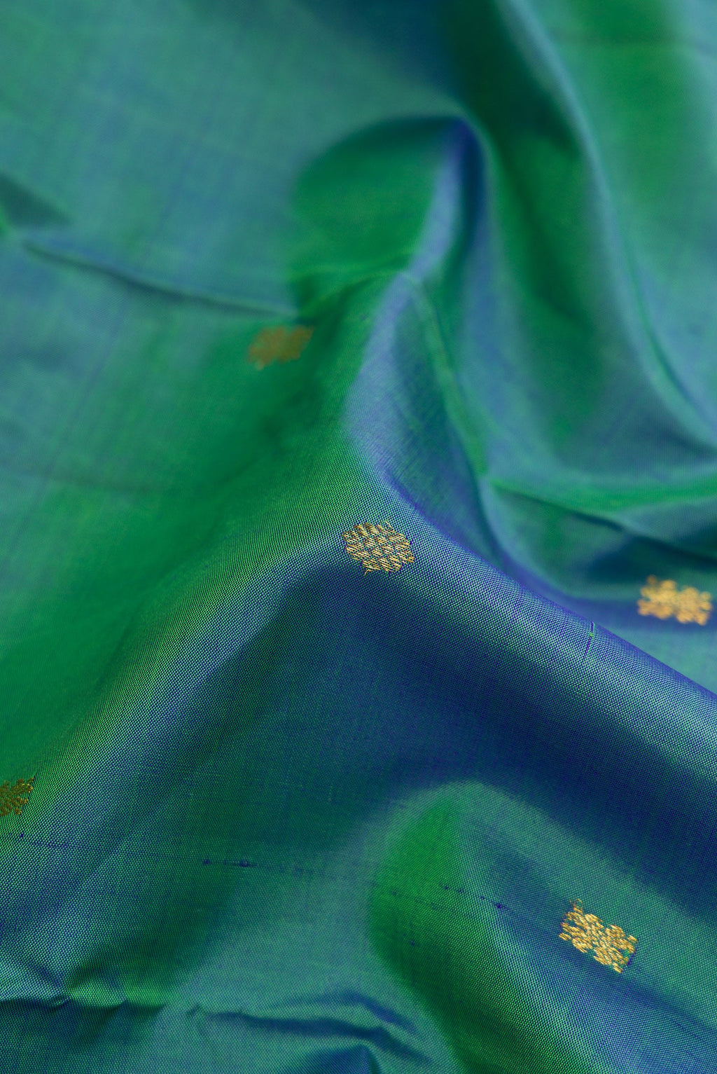 Close up of Peacock Blue Dual Tone Kanchipuram Silk Saree with Zari Butta on the body and Zari Border.  displaying folds