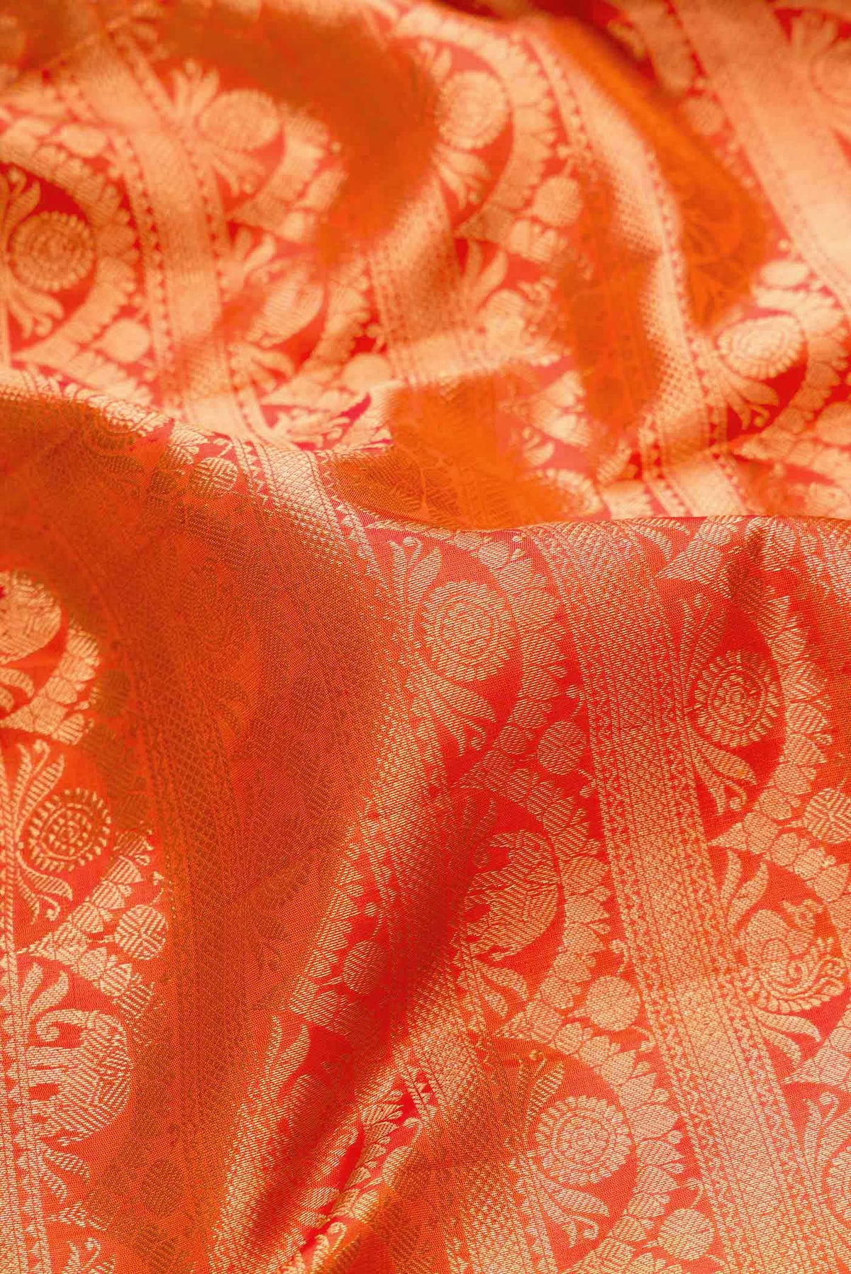 Close up of Coral Dual Tone Kanchipuram Silk Saree with Zari Brocade on the body and Zari Border.  displaying folds